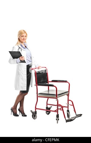 Full length portrait of a nurse holding a clipboard next to a wheelchair isolated on white background Stock Photo