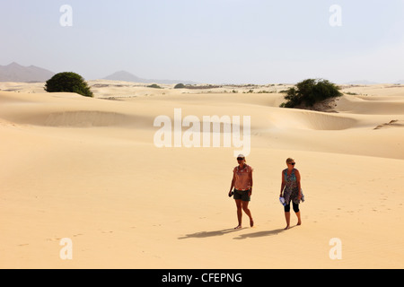 View of two women tourists walking barefoot on hot empty desert sand dunes. Deserto de Viana, Boa Vista, Cape Verde Islands, Africa Stock Photo