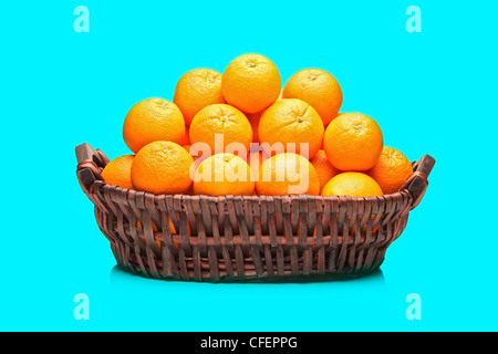 Many oranges in a basket isolated on turquoise background Stock Photo