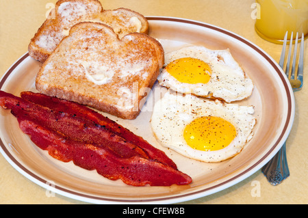 A breakfast of fried eggs, turkey bacon, toast, and juice Stock Photo