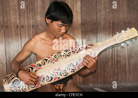 Orang Ulu man plays his traditional sape in Sarawak, Borneo, Malaysia Stock Photo