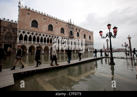 Tourists walking on footbridges during high tide in St. Mark's square, Doge's Palace in the background, Venice, Veneto, Italy Stock Photo