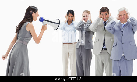 Woman yelling in a megaphone at business people with their hands over their ears Stock Photo