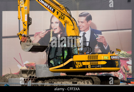 JCB excavator and aspirational poster on wall during building of 2012 Olympic Westfield City shopping centre, Stratford. Stock Photo