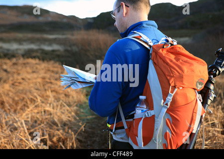 Man looking at a map in the countryside of Scotland Stock Photo
