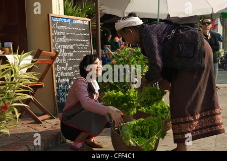 Young woman buying salat from elderly lady for a restaurant, Luang Prabang, Laos Stock Photo