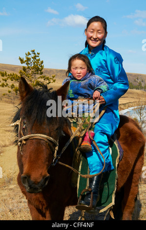 Young Mongolian woman and child in traditional costume (deel) riding a horse, Province of Khovd, Mongolia, Central Asia, Asia Stock Photo