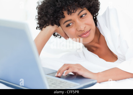 Cute black haired woman lying on her bed Stock Photo