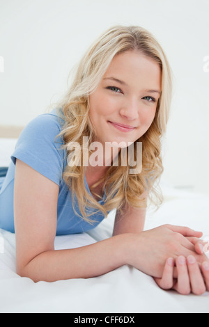 Close up, woman slightly smiling with hands together on the bed Stock Photo