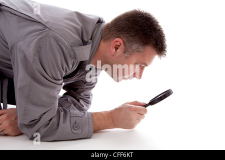 Man with raincoat is looking with magnifying glass over white background Stock Photo