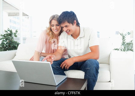 Man and woman sitting on the couch using the laptop and smiling Stock Photo