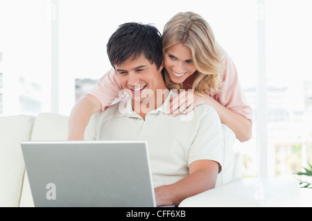 Man using laptop with woman watching him beside his head as they smile Stock Photo