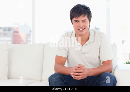 Man sitting on the couch hands together and smiling Stock Photo