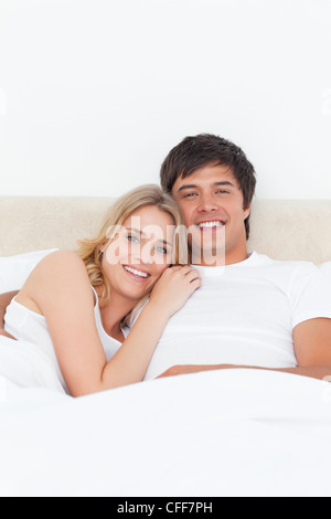 Close up, woman and man in bed smiling as the woman lays her head on his shoulder Stock Photo
