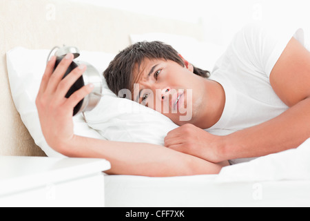 Man in bed, awake looking at his alarm clock Stock Photo
