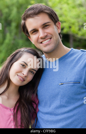 Young lovely couple standing side by side in a park Stock Photo