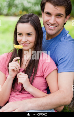 Young smiling couple standing together in the countryside with a flower Stock Photo