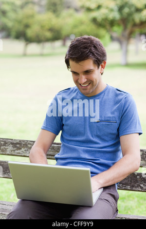 Young man working on his laptop while sitting on a bench Stock Photo