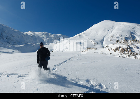 Man walking through thick powder in snowy mountain landscape near Col de Pause, Ariege, Pyrenees, France. Stock Photo