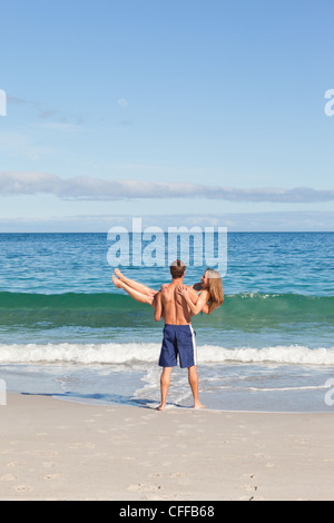 Young man carrying his girlfriend on the beach Stock Photo
