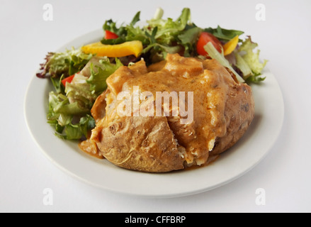 baked potato with curry filler on a plate with side salad Stock Photo