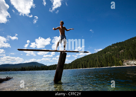 A young man balances on a teeter totters high above a lake in Idaho. Stock Photo