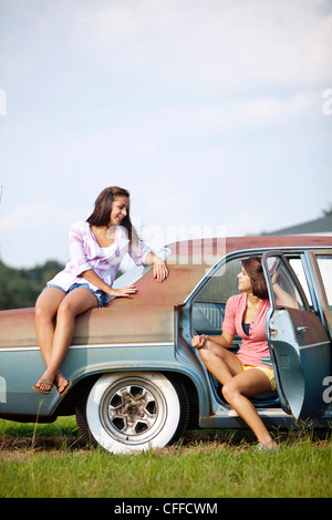 Two sisters hang out on a classic car. Stock Photo