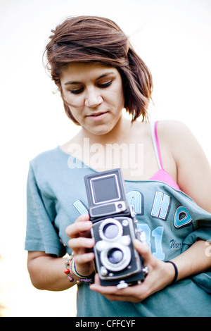 A young woman takes a photo with a classic camera. Stock Photo