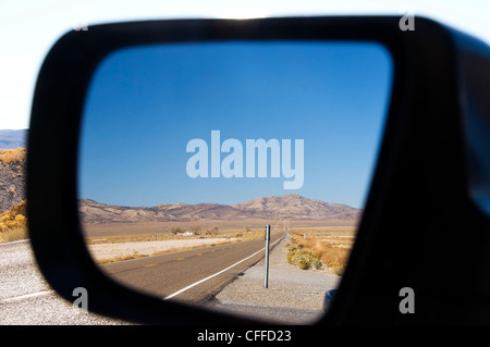Highway 50 in Nevada, better known as the Loneliest Road in America, is reflected in a rearview mirror.