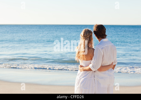 Back view of couple standing at the beach Stock Photo