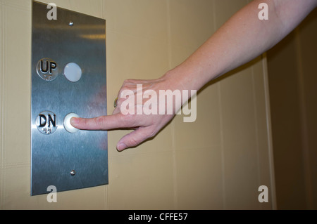 Woman's Finger Pressing Elevator Down Button Stock Photo