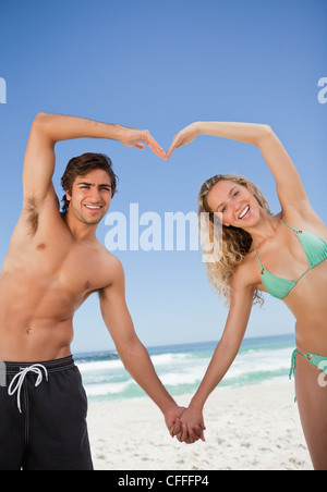 Smiling attractive young people making a heart shape together Stock Photo