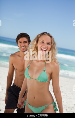 Smiling attractive woman holding her boyfriend's hand on the beach Stock Photo