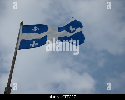Quebec Fleur de Lys flag waving with cloudy sky in background Stock Photo