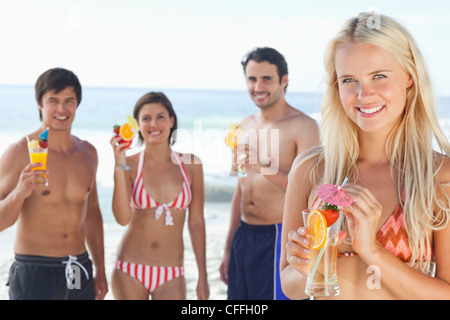 Woman enjoying a cocktail while her three friends stand behind her Stock Photo