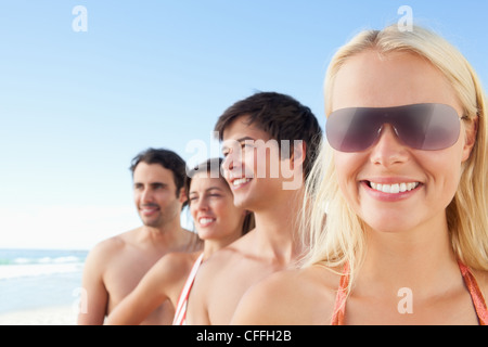 Woman smiling while wearing sunglasses as her friends look to the side Stock Photo