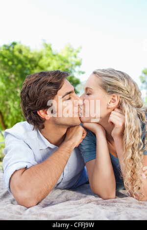 Couple kissing while lying on the lawn Stock Photo