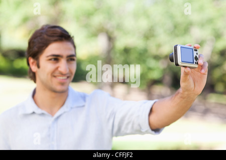 Side view of a smiling man in the park taking a picture of himself Stock Photo