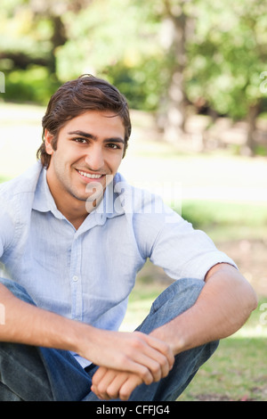 Smiling man sitting in the park Stock Photo