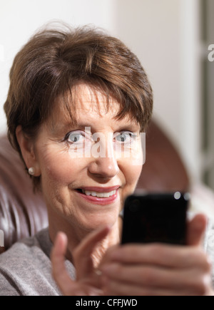 Attractive senior woman happy using technology; mobile phone/ smart phone Stock Photo