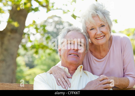 Man embracing with his friend as he sits on a bench Stock Photo