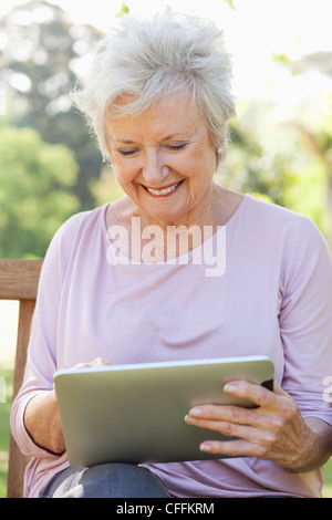 Woman using a tablet while sitting on a bench Stock Photo