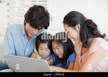 Family using the laptop while sitting on the couch Stock Photo