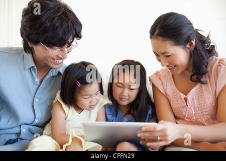 The entire family sitting on the couch while using the tablet Stock Photo