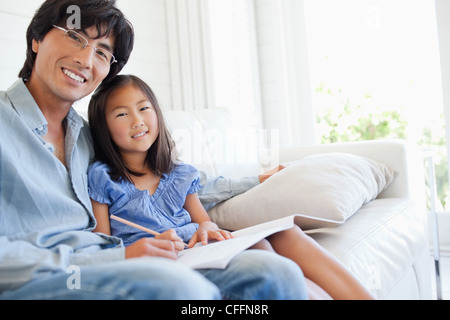 Side view of a daughter and father sitting on the couch Stock Photo