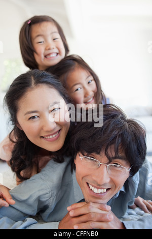 A smiling family lying on the floor on top of each other Stock Photo