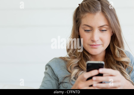 A woman sits on the couch texting on her phone Stock Photo