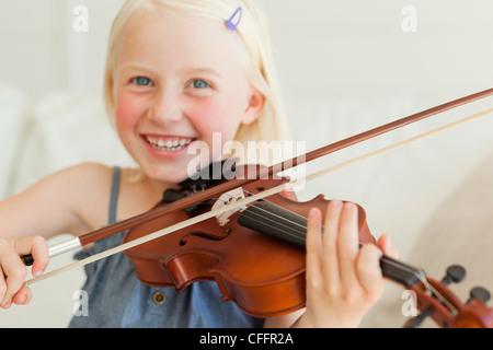 A cute girl enjoys playing the violin Stock Photo