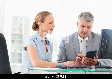 Boss using a calculator with his secretary Stock Photo
