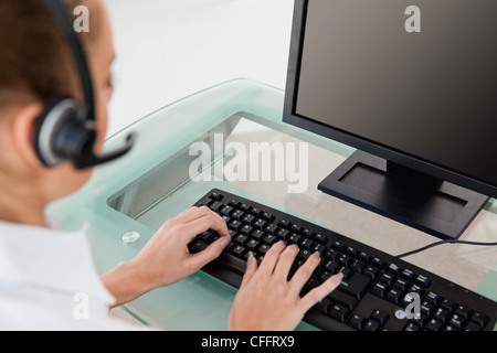 Businesswoman with headset using computer Stock Photo - Alamy